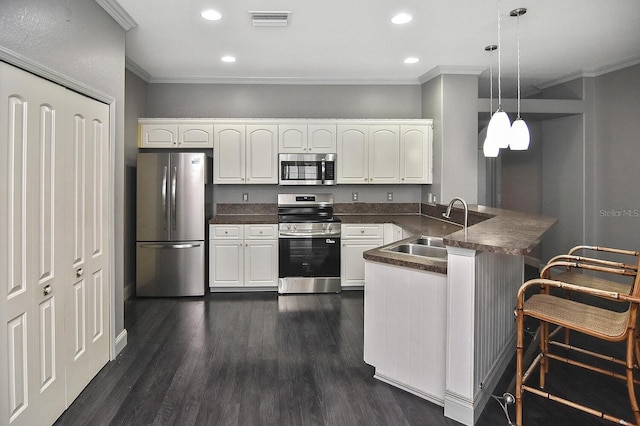 kitchen with a peninsula, dark countertops, stainless steel appliances, and a sink