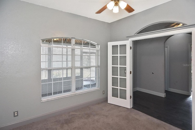 spare room featuring ceiling fan, carpet floors, baseboards, and arched walkways