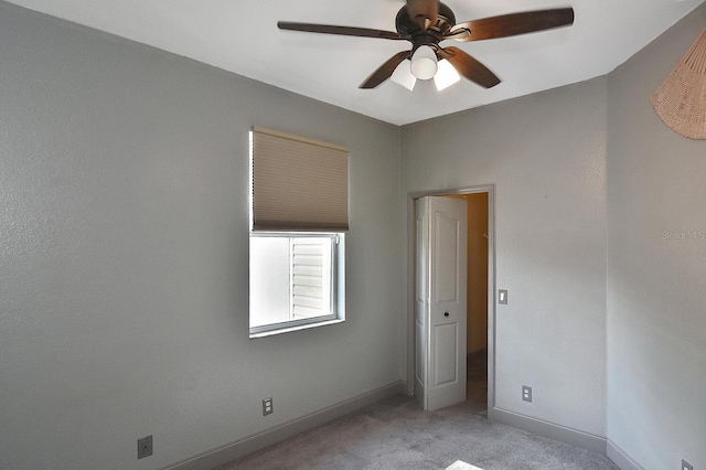 unfurnished room with light colored carpet, baseboards, and a ceiling fan