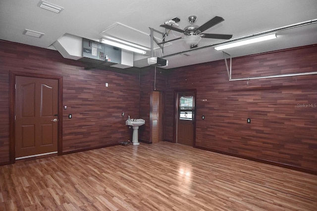 interior space featuring ceiling fan, wooden walls, and wood finished floors