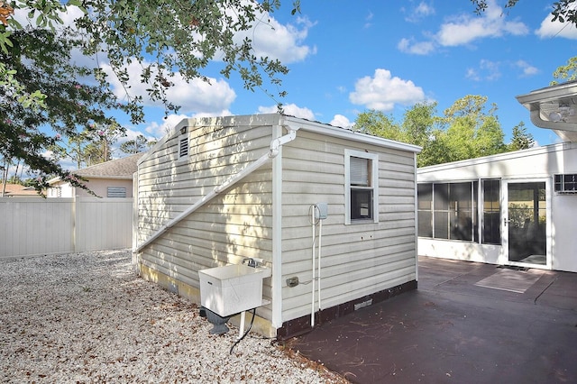 view of outbuilding featuring a sunroom and fence