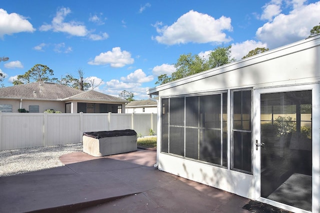 view of patio / terrace with a sunroom, a hot tub, and a fenced backyard