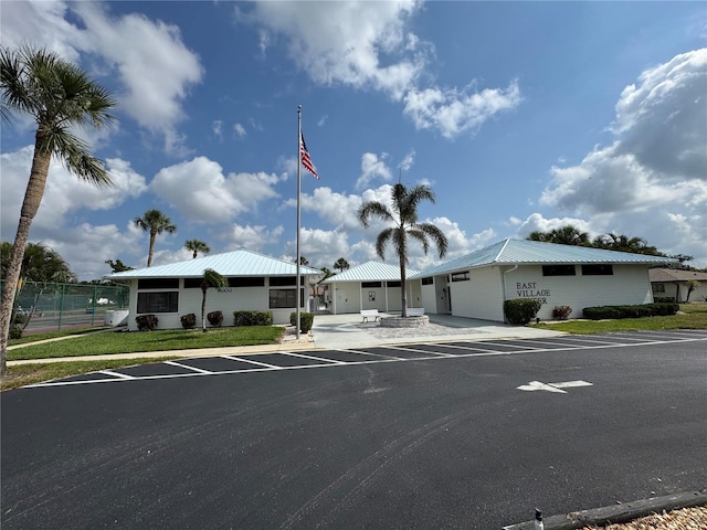 view of front facade featuring metal roof, uncovered parking, and fence