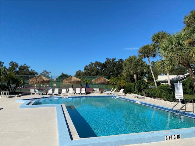 community pool with a patio and fence