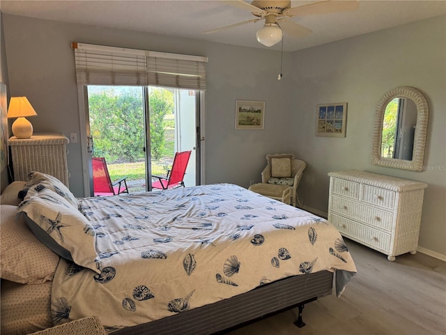 bedroom featuring access to outside, wood finished floors, multiple windows, and a ceiling fan