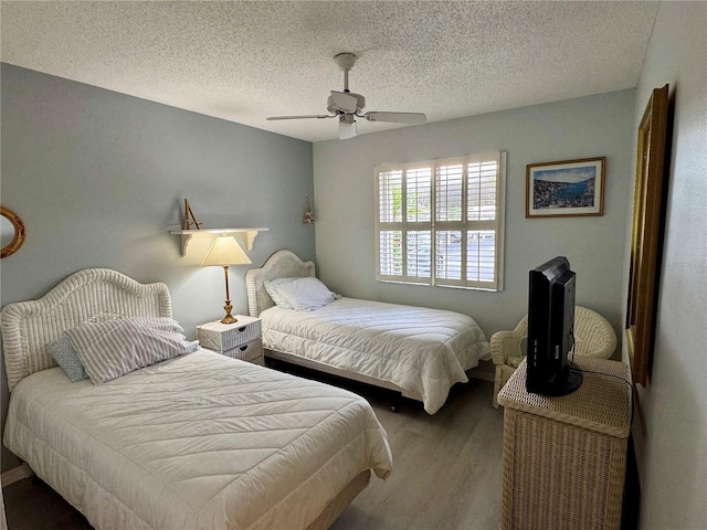 bedroom with wood finished floors, ceiling fan, and a textured ceiling