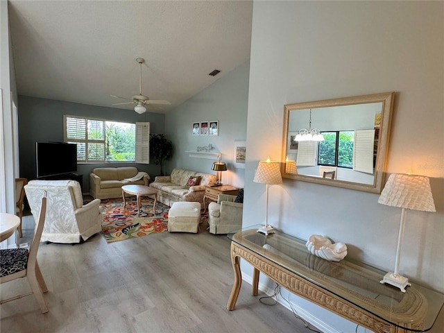 living area with high vaulted ceiling, wood finished floors, visible vents, and ceiling fan with notable chandelier