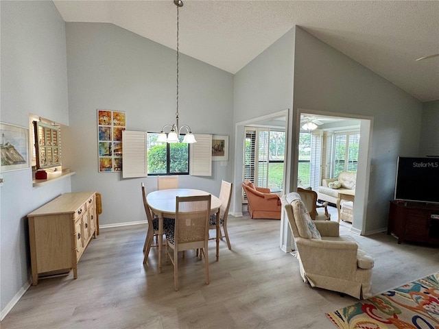 dining area with high vaulted ceiling, light wood-style flooring, baseboards, a chandelier, and a ceiling fan