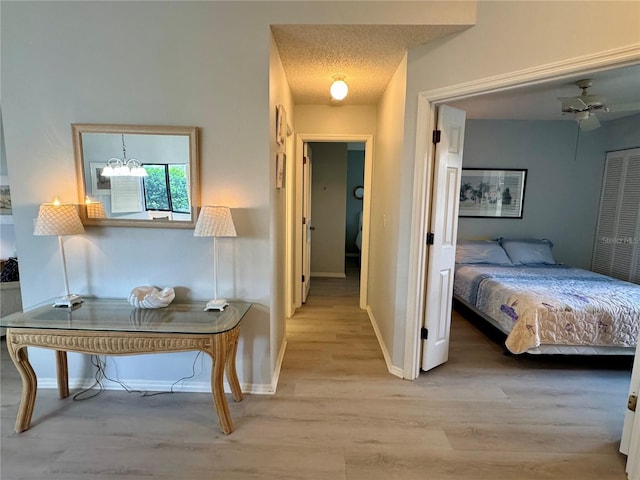 corridor featuring light wood-style flooring, baseboards, and a chandelier