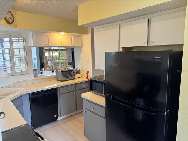 kitchen with black appliances, light countertops, gray cabinets, light wood-style flooring, and a textured ceiling