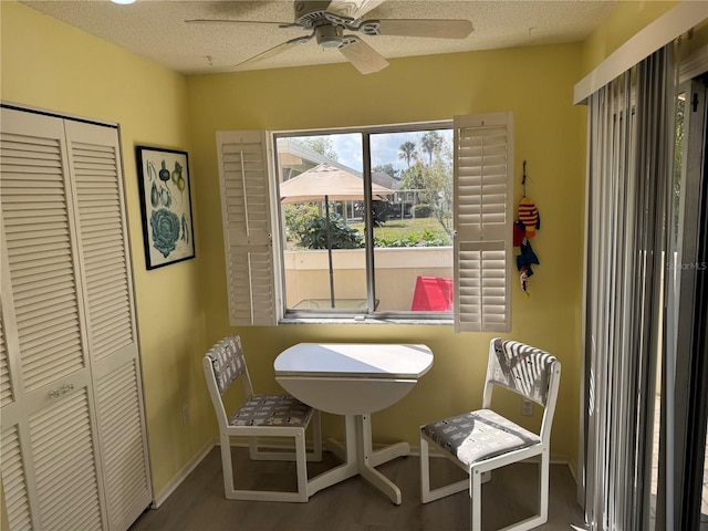 dining space with a ceiling fan, wood finished floors, baseboards, and a textured ceiling