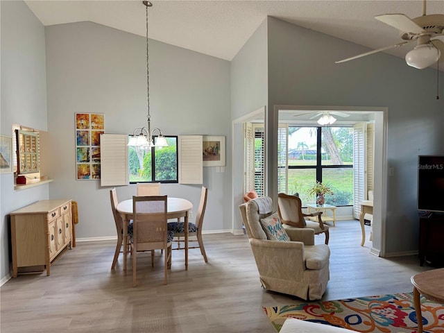 dining room with a ceiling fan, high vaulted ceiling, baseboards, a chandelier, and light wood-style floors