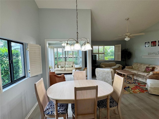 dining room with a chandelier, wood finished floors, a ceiling fan, high vaulted ceiling, and baseboards