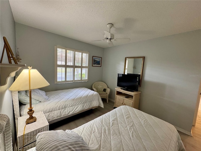 bedroom featuring baseboards, a ceiling fan, a textured ceiling, and wood finished floors