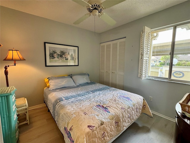bedroom featuring wood finished floors, baseboards, a closet, and a ceiling fan