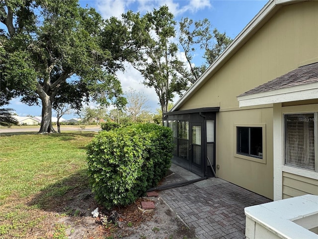view of home's exterior featuring a lawn, a patio, and roof with shingles