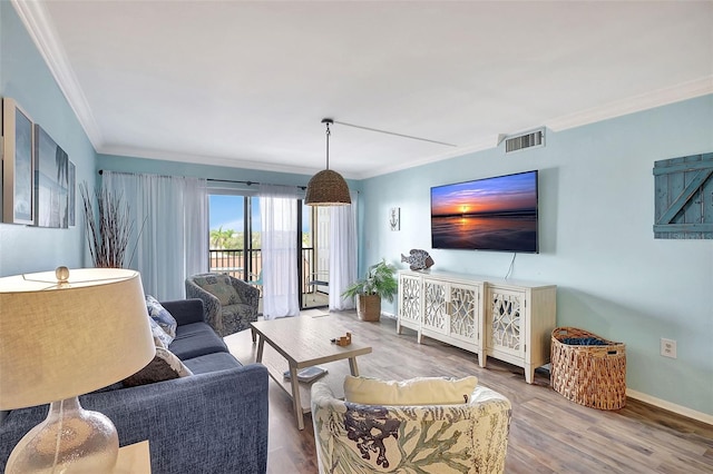 living area featuring baseboards, ornamental molding, visible vents, and wood finished floors