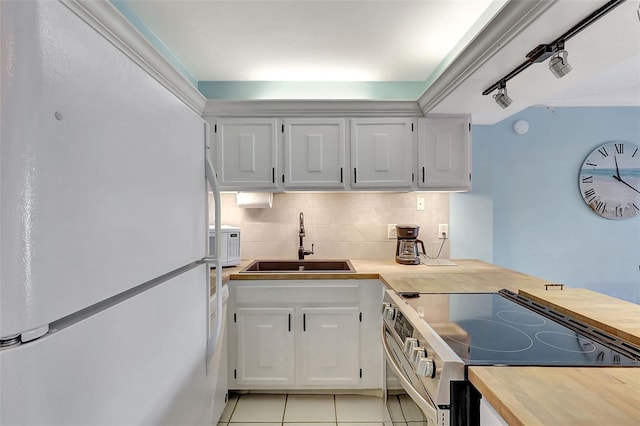 kitchen with a sink, white appliances, wood counters, decorative backsplash, and light tile patterned floors