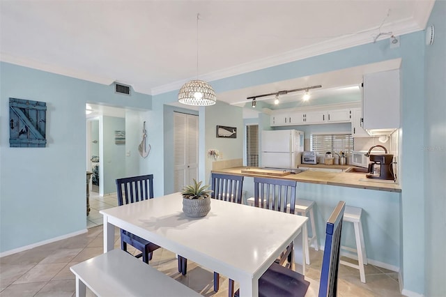 dining area with rail lighting, ornamental molding, light tile patterned floors, and visible vents
