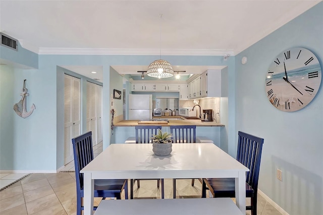 dining room with crown molding, baseboards, light tile patterned floors, and visible vents