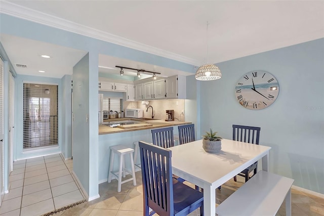 dining space featuring ornamental molding, light tile patterned flooring, track lighting, visible vents, and baseboards