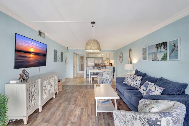 living room featuring light wood finished floors, visible vents, and ornamental molding