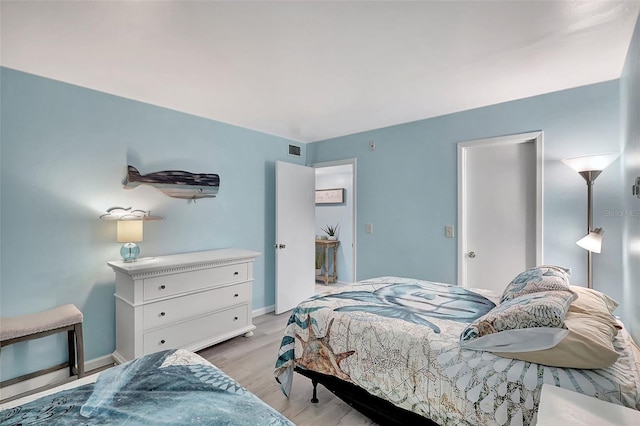 bedroom featuring light wood-type flooring, visible vents, and baseboards