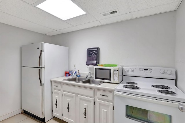 kitchen featuring a drop ceiling, a sink, white cabinetry, visible vents, and white appliances