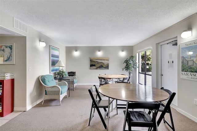 dining space with light carpet, a textured ceiling, baseboards, and visible vents
