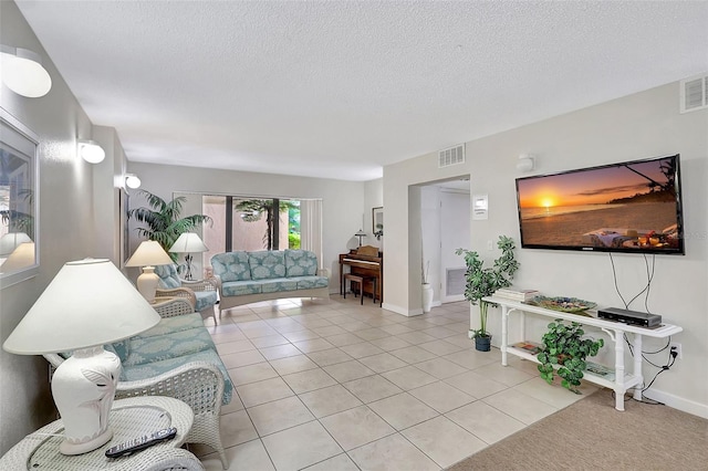 living room featuring light tile patterned floors, baseboards, visible vents, and a textured ceiling