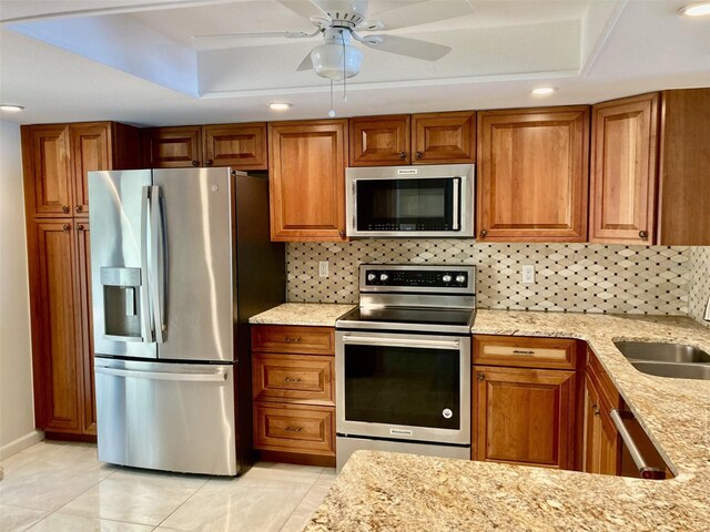 6430 Sun Eagle Ln Unit 203, Bradenton, FL 34210 - kitchen with stainless steel appliances, a raised ceiling, brown cabinets, light stone counters, and recessed lighting
