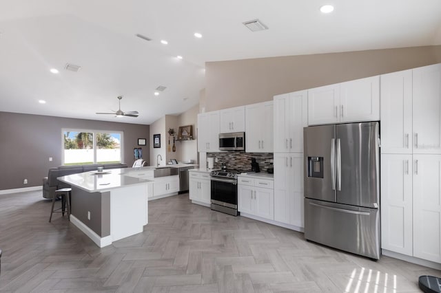 kitchen with stainless steel appliances, baseboards, a ceiling fan, decorative backsplash, and a sink