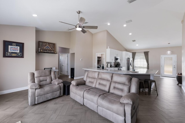 living room featuring baseboards, a ceiling fan, high vaulted ceiling, and recessed lighting