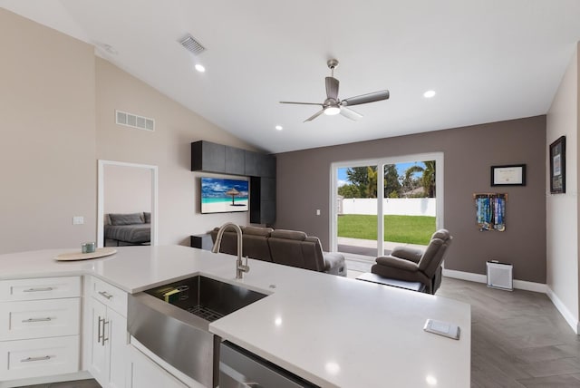 kitchen with a sink, open floor plan, light countertops, ceiling fan, and white cabinetry
