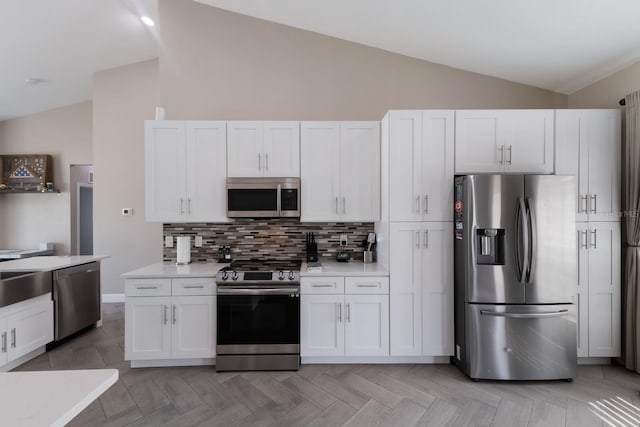 kitchen featuring stainless steel appliances, lofted ceiling, tasteful backsplash, light countertops, and white cabinets