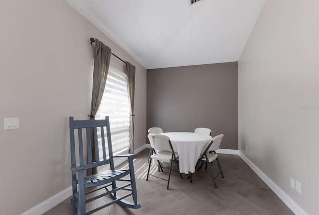 dining room with baseboards and lofted ceiling