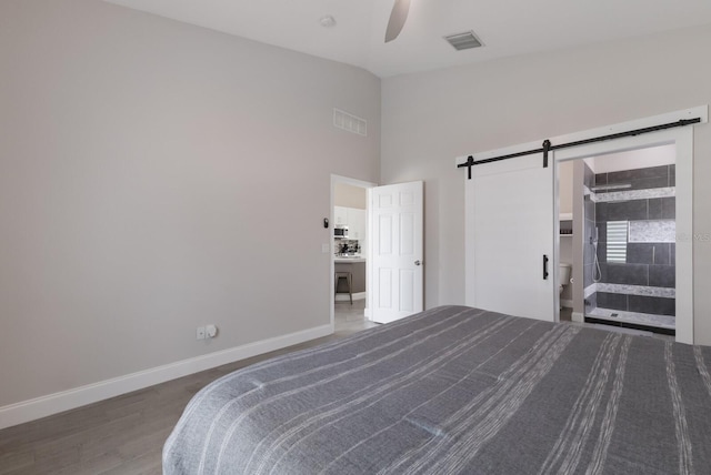 bedroom with a barn door, baseboards, wood finished floors, high vaulted ceiling, and a ceiling fan