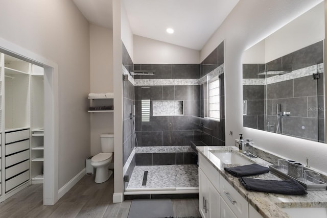 full bathroom featuring a shower stall, wood finished floors, toilet, double vanity, and lofted ceiling