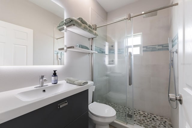 bathroom featuring toilet, a shower stall, and vanity
