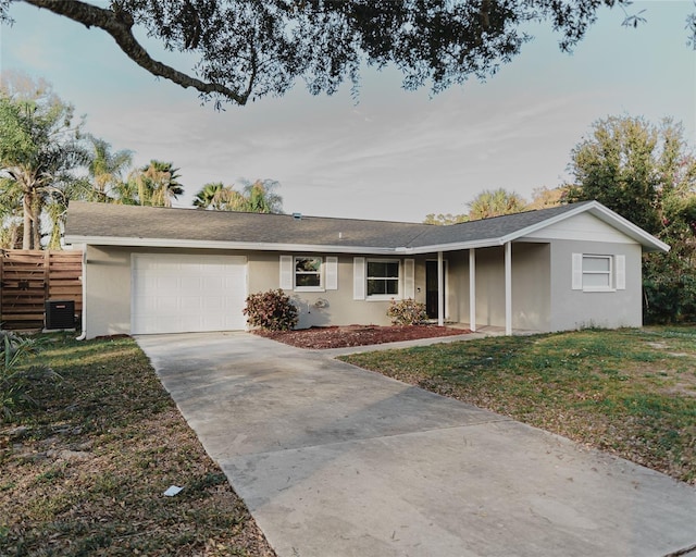 ranch-style house with driveway, an attached garage, central AC, and stucco siding