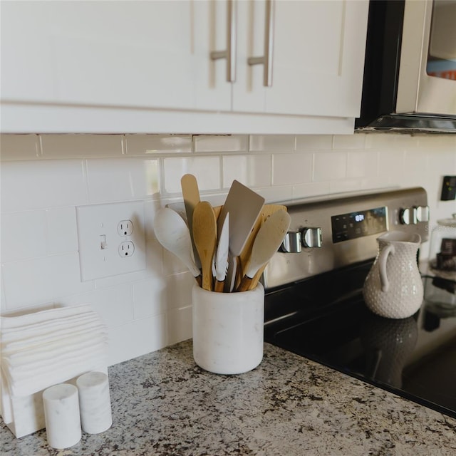kitchen view of backsplash, stainless steel appliances, and light stone countertops