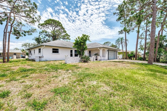 rear view of house with a garage, a lawn, driveway, and stucco siding