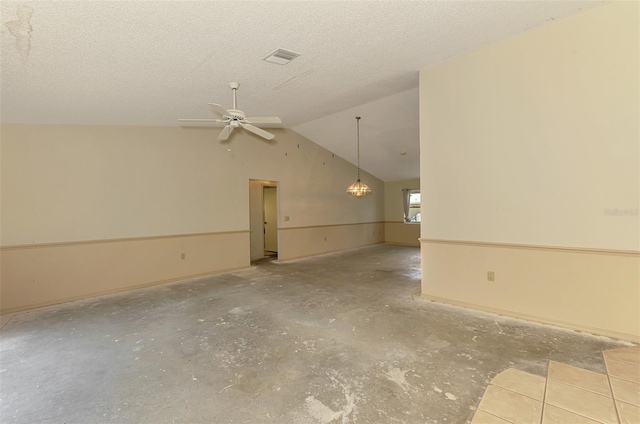spare room featuring ceiling fan, vaulted ceiling, unfinished concrete flooring, baseboards, and a textured ceiling