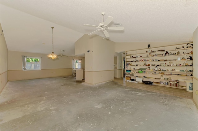empty room with lofted ceiling, ceiling fan, concrete flooring, and a textured ceiling