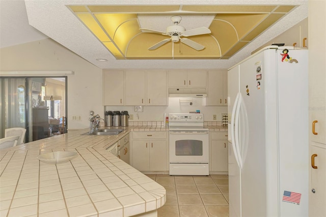 kitchen with white appliances, tile counters, under cabinet range hood, a peninsula, and a ceiling fan