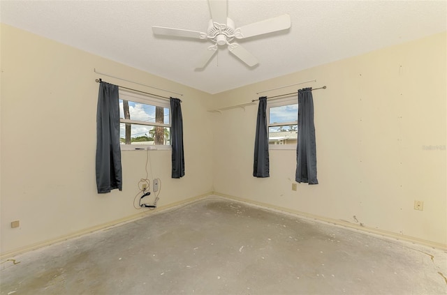 unfurnished room featuring baseboards, a ceiling fan, and concrete flooring