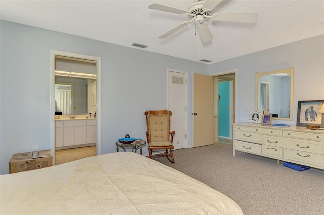 bedroom with light colored carpet, ensuite bathroom, a ceiling fan, and a textured ceiling