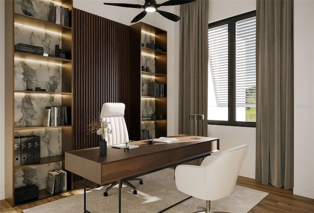 home office with built in shelves, ceiling fan, and wood finished floors