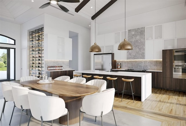 dining space with beam ceiling, light wood-style flooring, a ceiling fan, and high vaulted ceiling