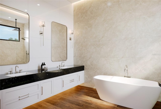 full bath with a freestanding tub, double vanity, a sink, and wood finished floors
